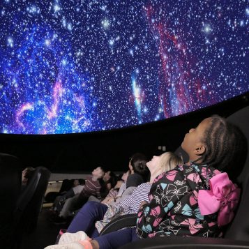 Audience watching a star-filled planetarium show
